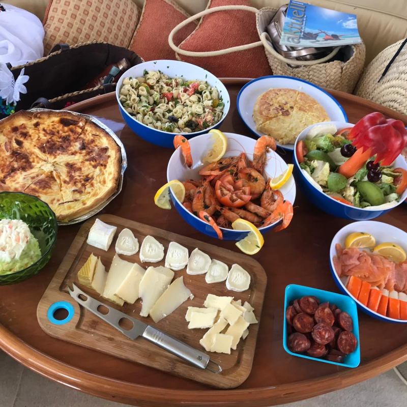 Assorted dishes on a table include shrimp, quiche, cheese, salad, smoked salmon, and pasta salad.