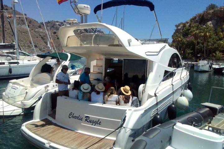 People sitting on a yacht in a marina with a Spanish flag.