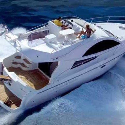 People enjoying a ride on a white yacht cruising through blue ocean waves.