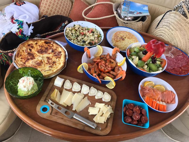 Table with assorted dishes including quiche, salad, cheese, shrimp, and cured meats.