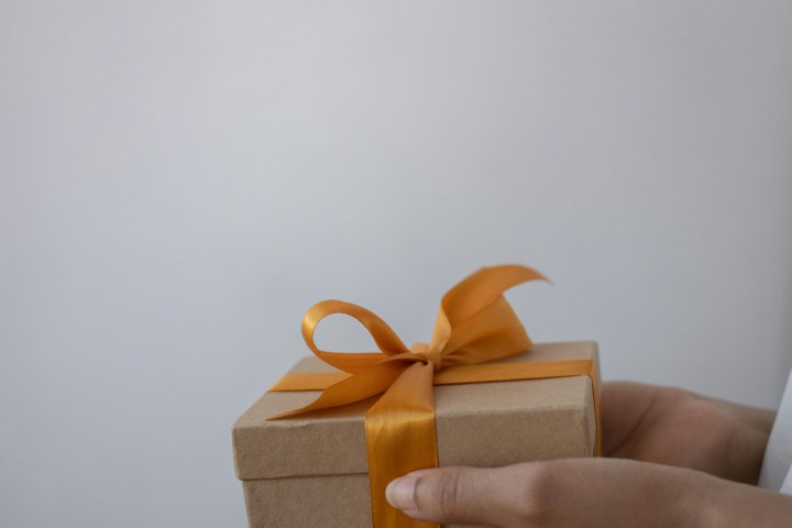 Hands holding a gift box with an orange ribbon and bow.