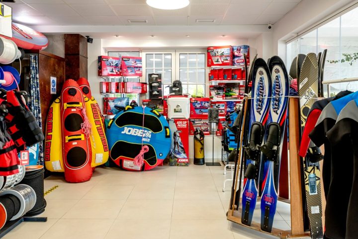 Sporting goods store with inflatables, water skis, and wetsuits displayed on racks.