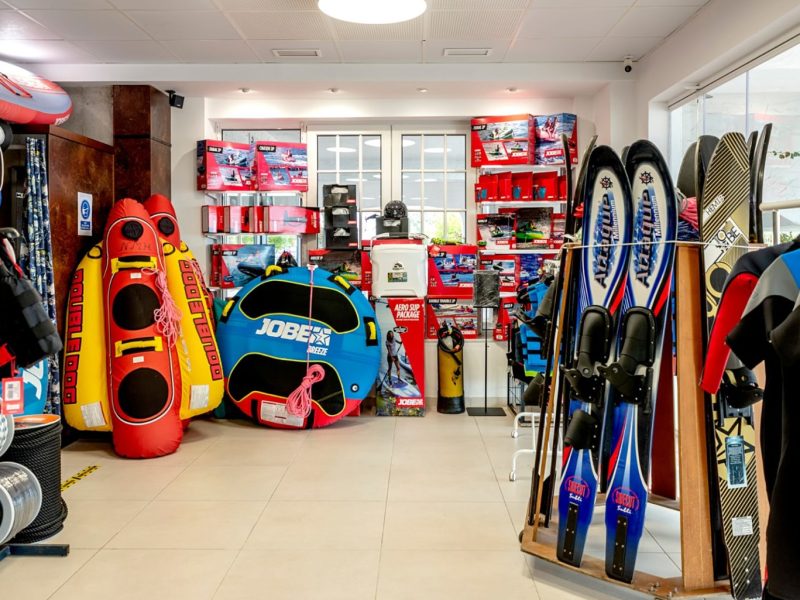 Sporting goods store with inflatables, water skis, and wetsuits displayed on racks.