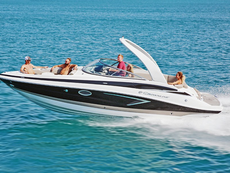 Boat with four people cruising on blue water under clear sky.