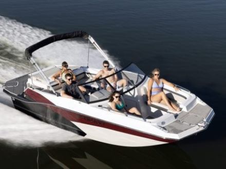 Five people relaxing on a speedboat moving quickly across the water.