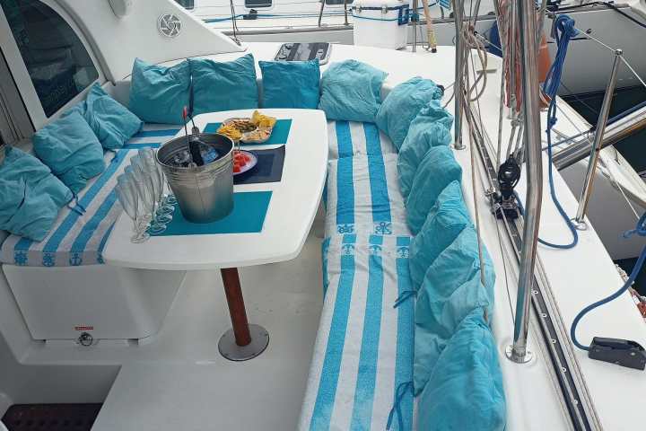 Cozy boat deck with blue cushions, table, snacks, and drinks setup for relaxation.