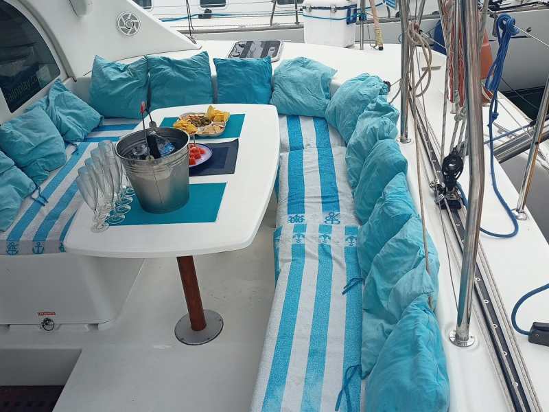 Cozy boat deck with blue cushions, table, snacks, and drinks setup for relaxation.