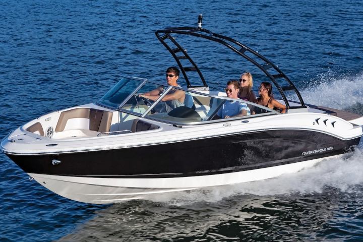 Speedboat with four people cruising on blue water.