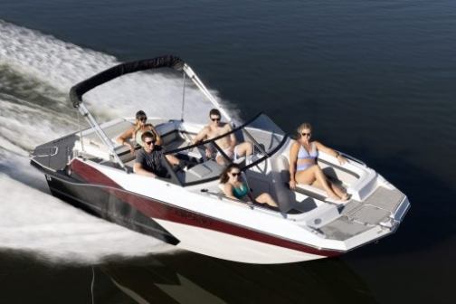 Five people relaxing on a speedboat in motion over calm water.