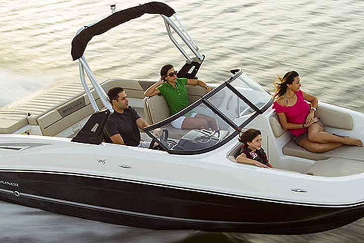 Four people in a speedboat cruising on water, with sunlight reflecting on the waves.