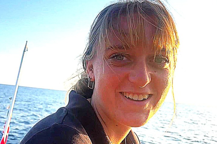 Person smiling on a boat with the sea and sky in the background.