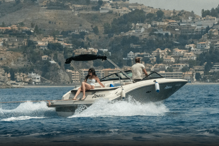 People on a speedboat in the ocean, cityscape background.
